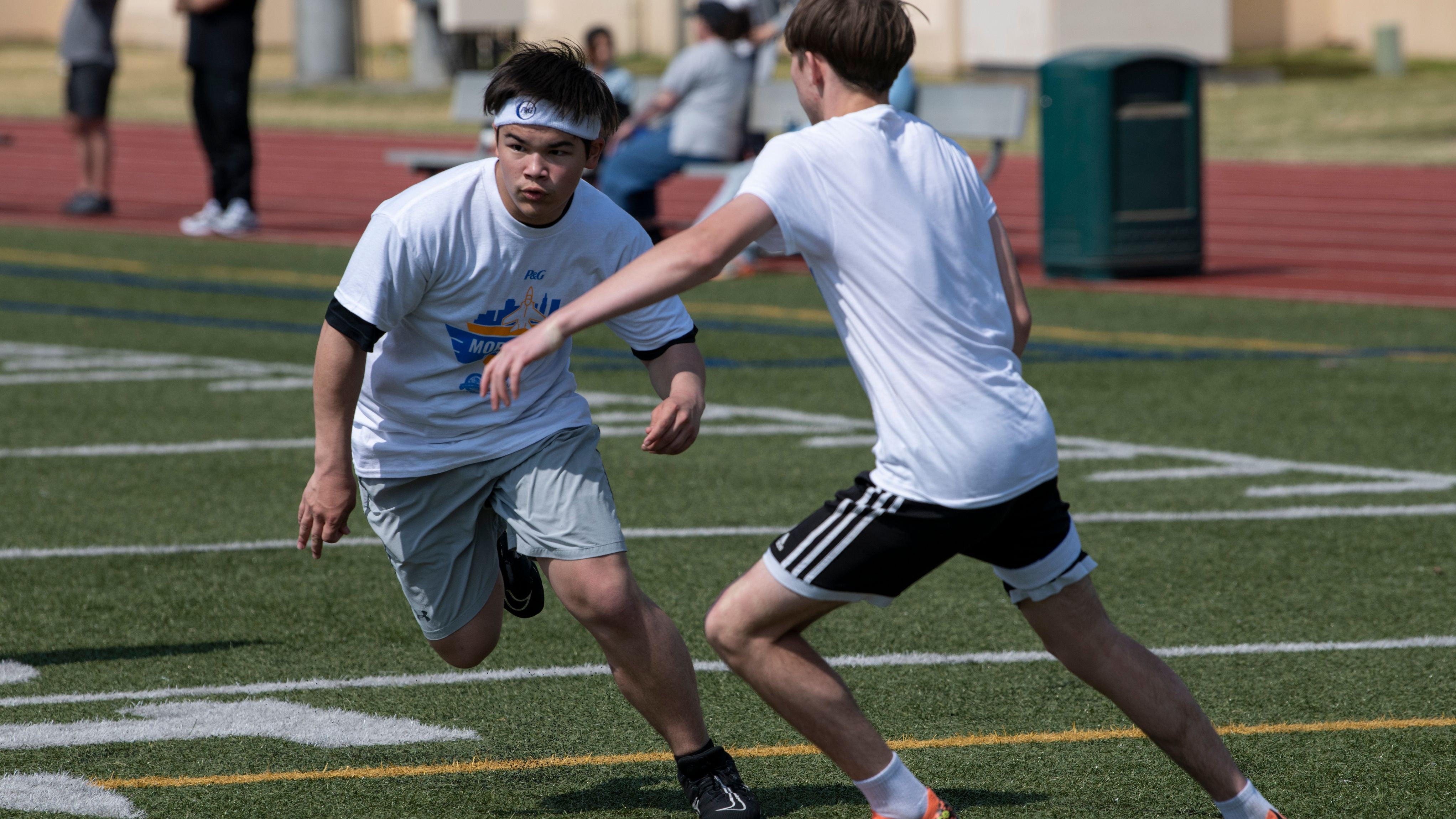 Two teen boys play football at a pro camp.