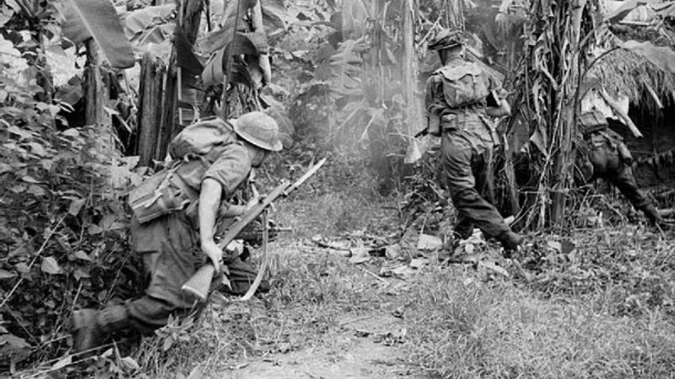 Men of the 36th Infantry Division advance through a banana grove.