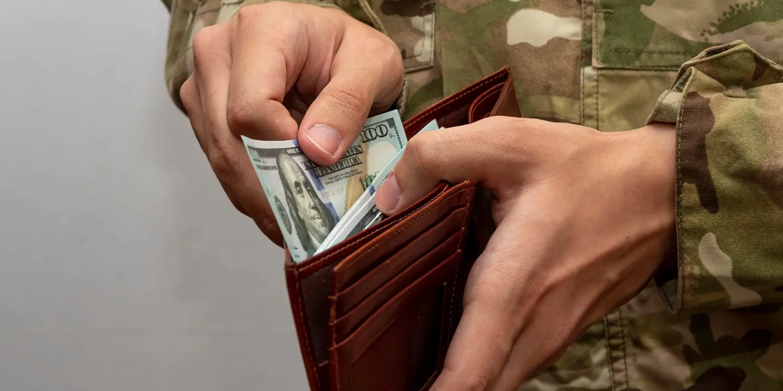 A man's hands go through bills in a wallet.