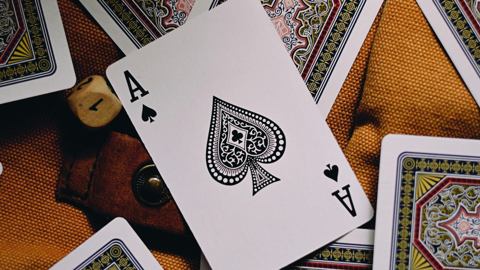 An Ace of Spades playing card laying face up on top of other playing cards.