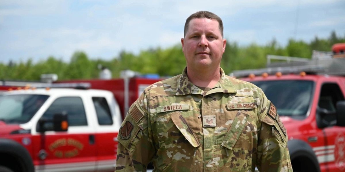 Air National Guard member in uniform with fire trucks in background