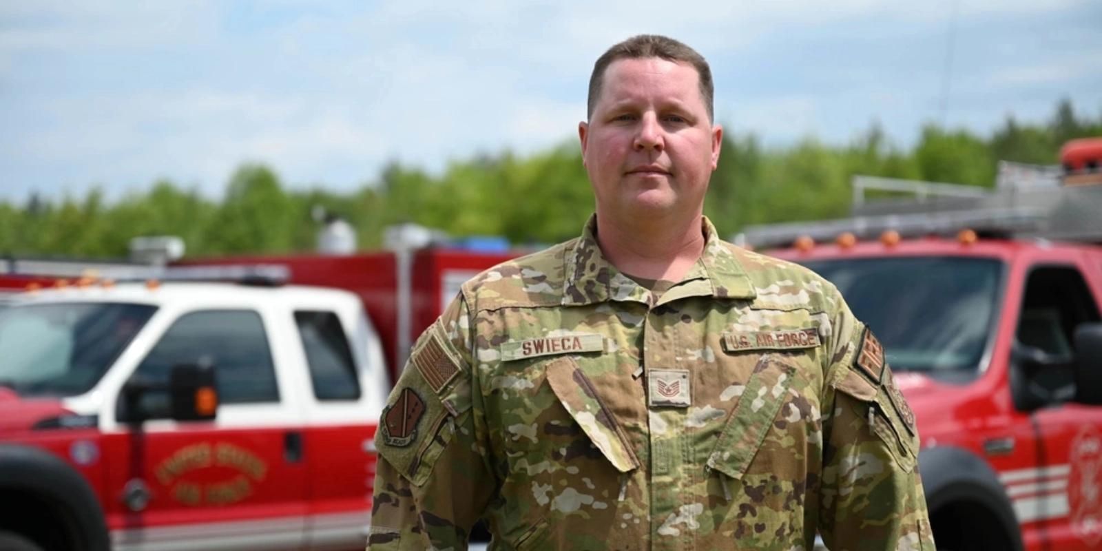Air National Guard member in uniform with fire trucks in background