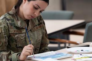 A female soldier paints in an art therapy session.