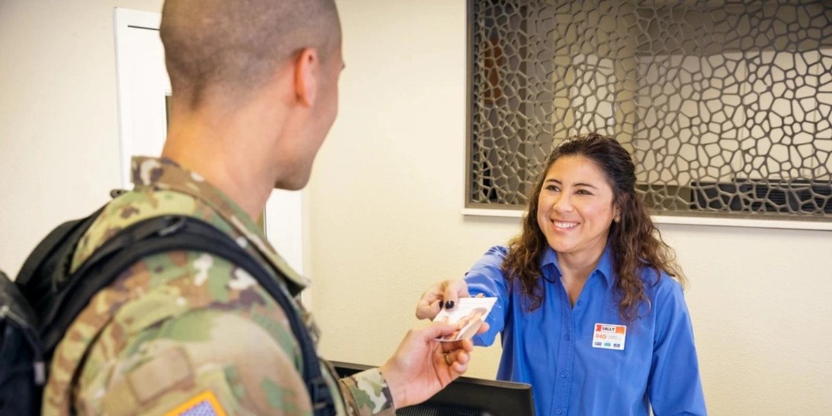 Service member in uniform receiving ID card from smiling clerk at military office desk