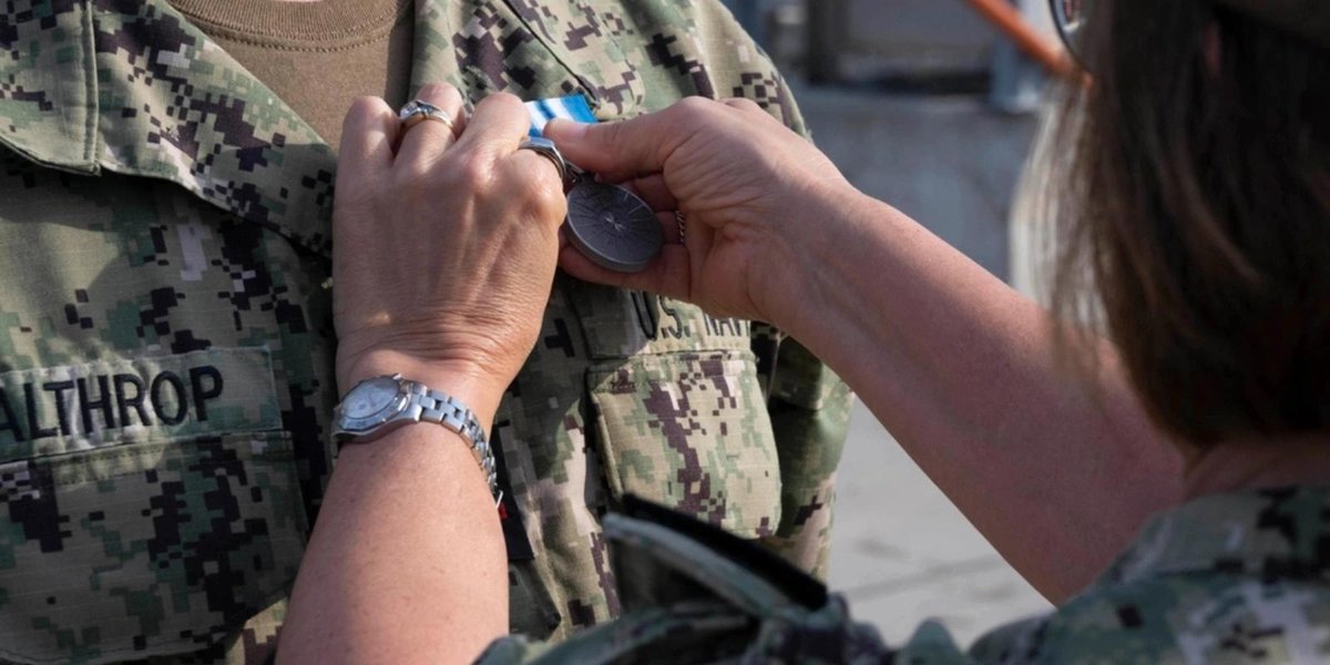 Sailor receiving the Navy Arctic Service Medal on uniform.