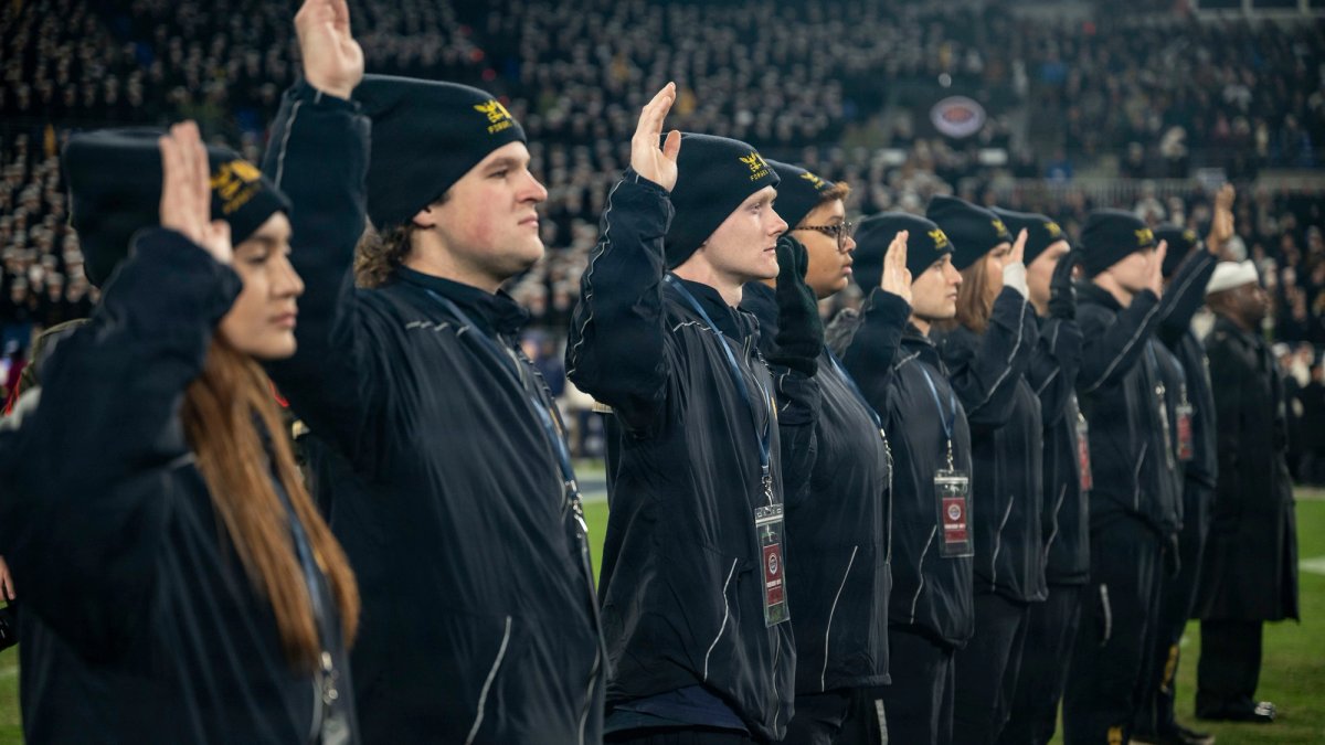 A row of new recruits raise their hands while taking an oath.