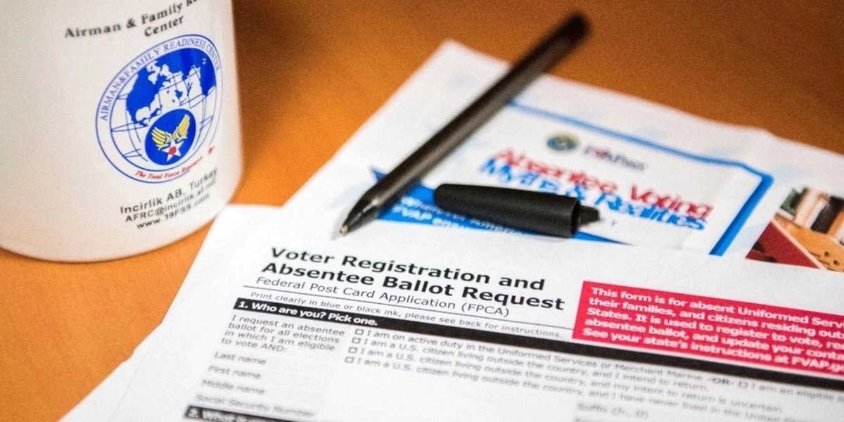 Voter registration and absentee ballot forms with Air Force mug on desk