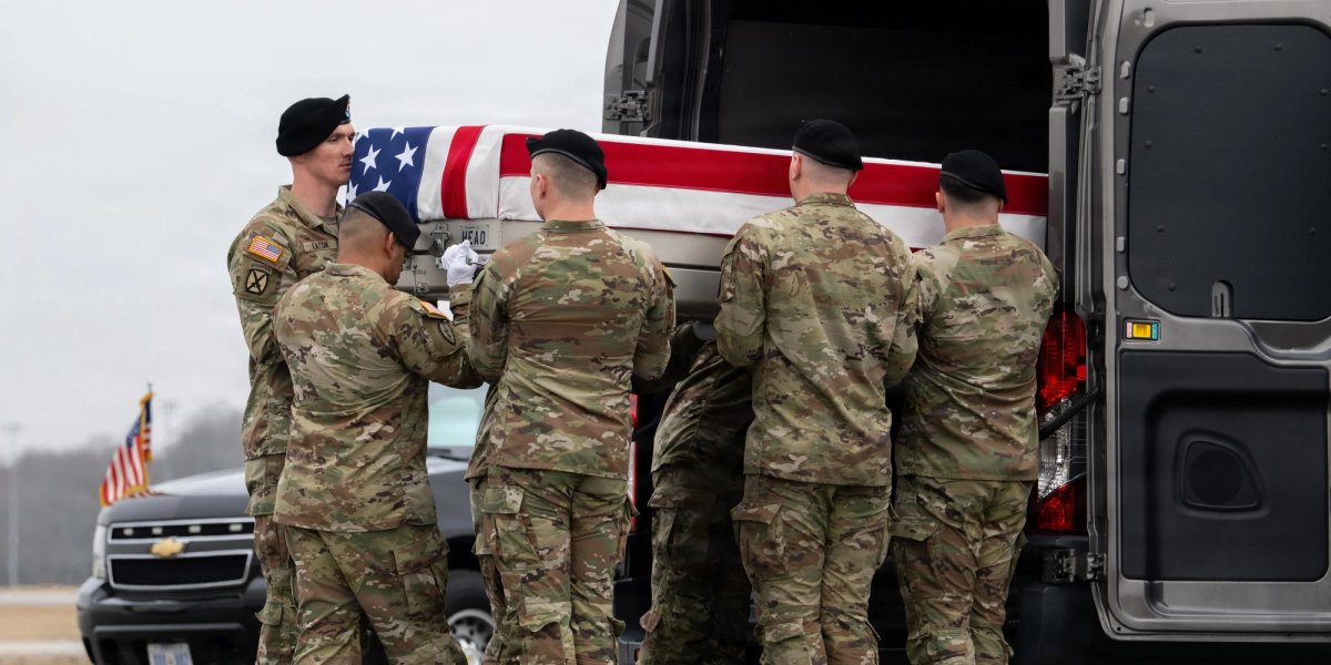 Six uniformed servicemen load a flag-covered casket into a van.
