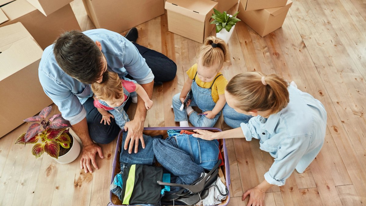 Family of four sits among moving boxes.