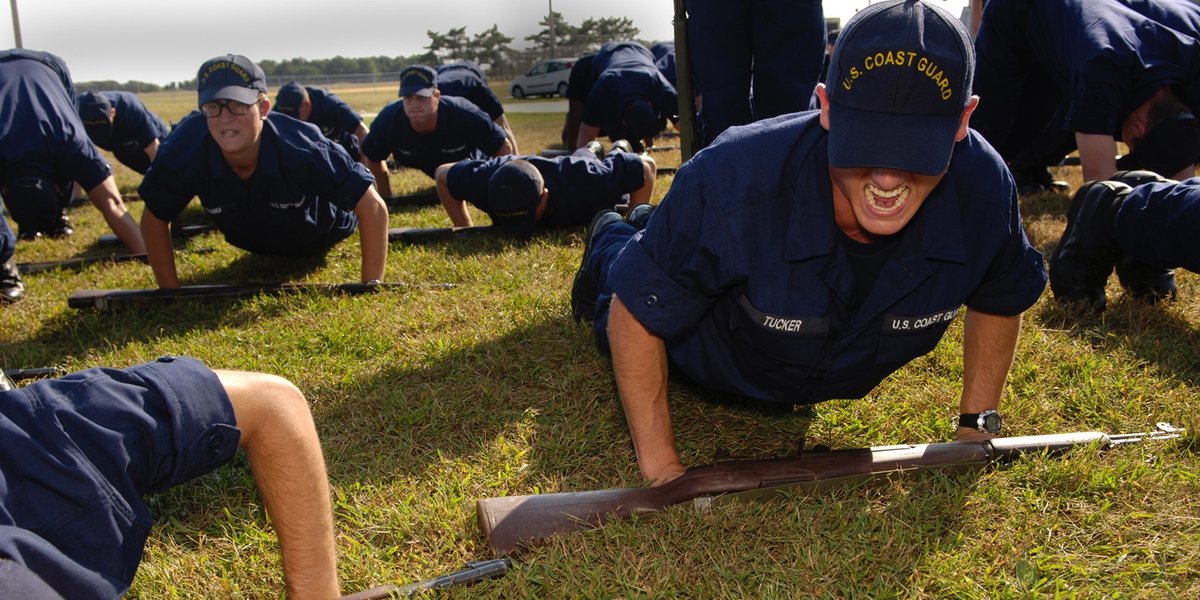 Rows of blue-uniformed recruits do pushups while in basic training.