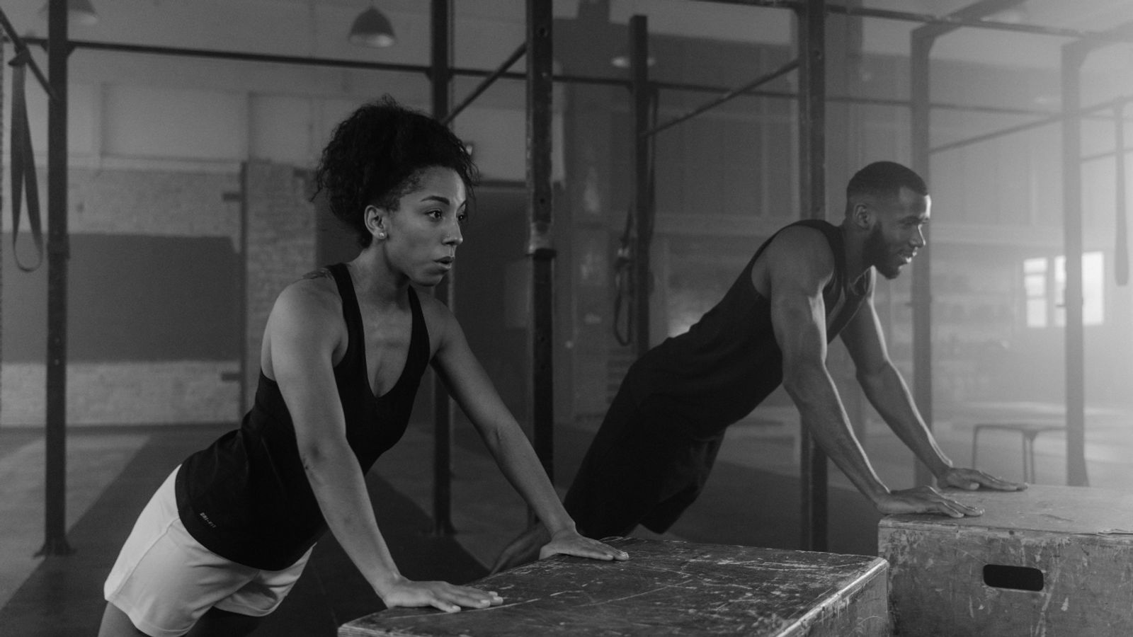 A man and woman working out with inclined push-ups on boxes.