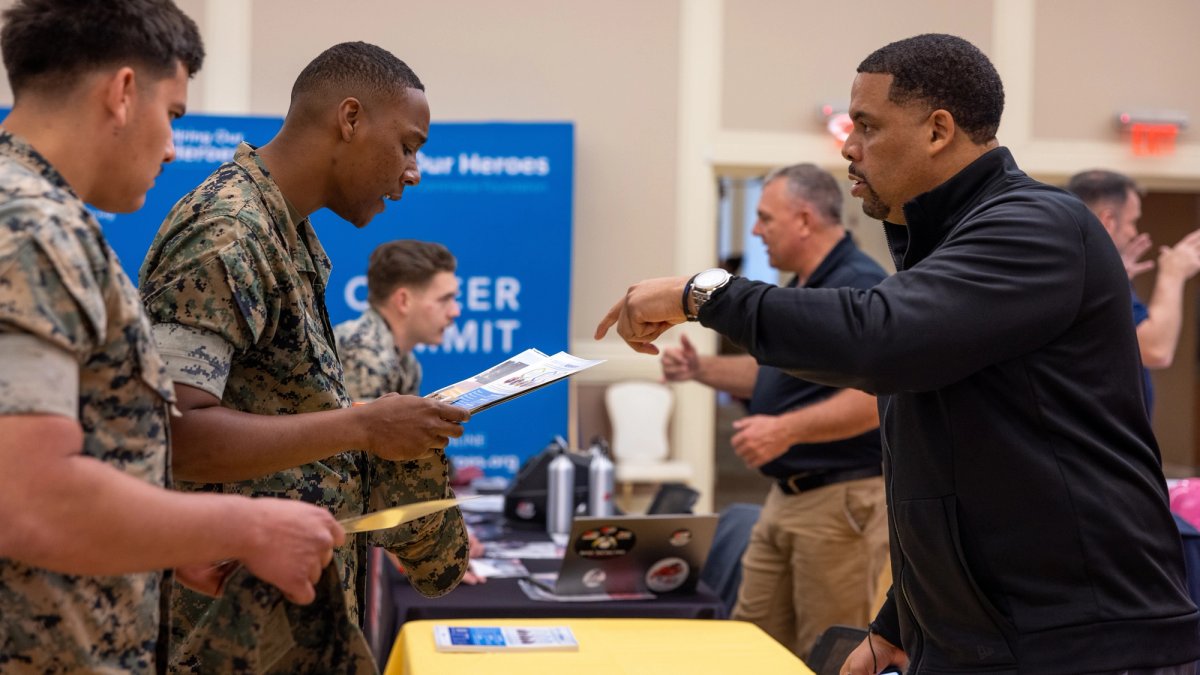 Uniformed soldiers ask questions at a job fair.