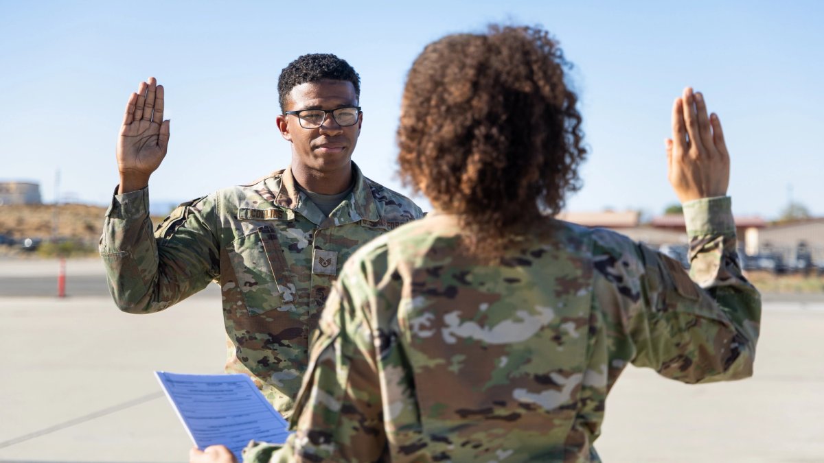 A soldier faces an enlisting officer and raises his hand while taking an oath.