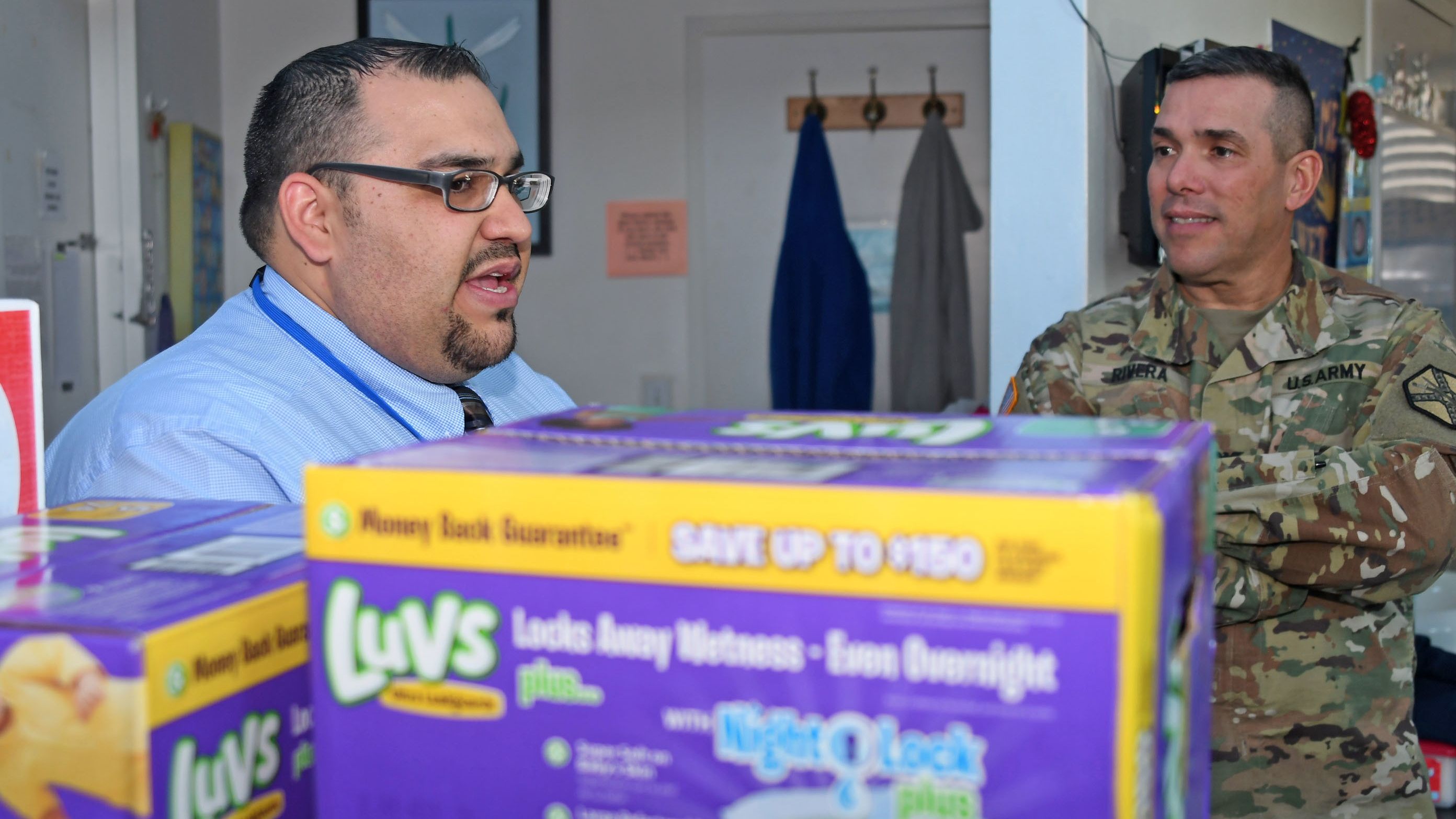 A soldier and worker discuss diapers in an office.