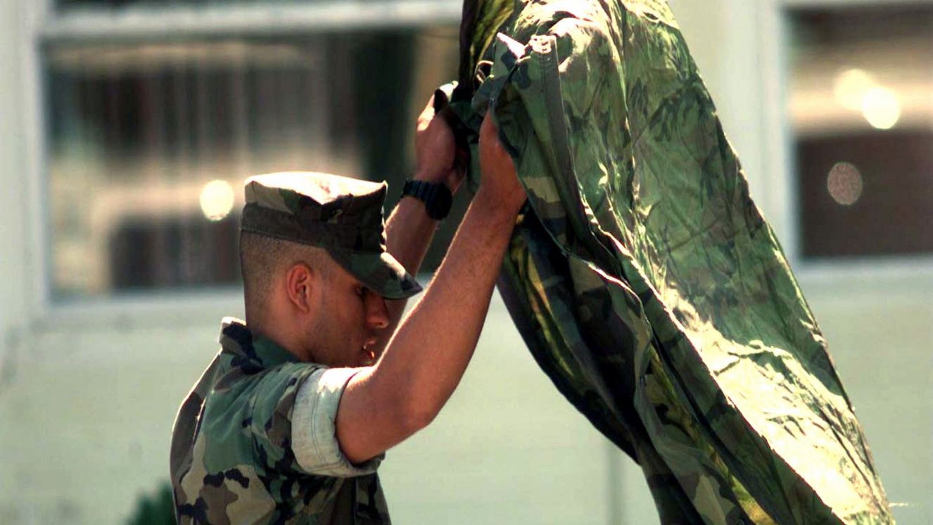 A soldier shakes off the dirt from his poncho.
