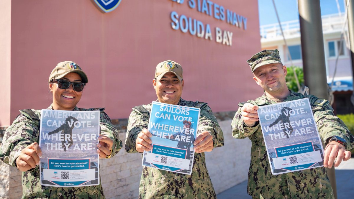 Three soldiers promote voting with flyers.
