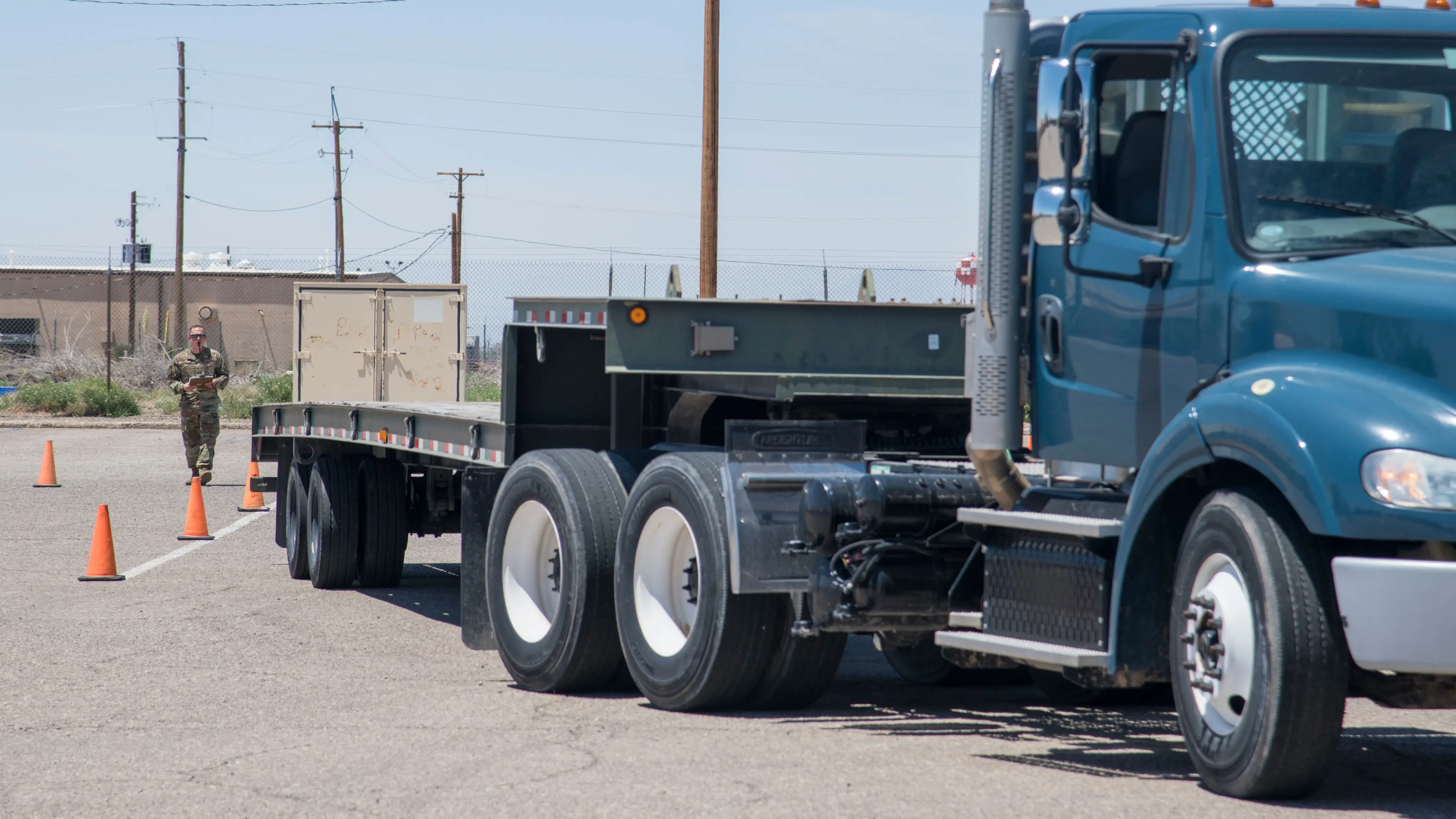 View of the side of a truck as an instructor guides a student driver through a reverse procedure.