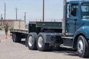 View of the side of a truck as an instructor guides a student driver through a reverse procedure.