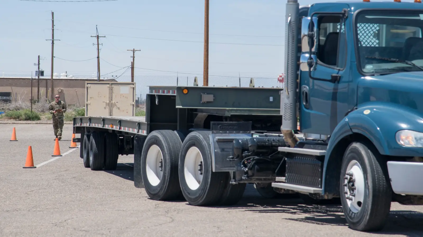 View of the side of a truck as an instructor guides a student driver through a reverse procedure.