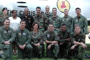 Portrait of a group of 14 servicepeople posing in front of a fighter jet.