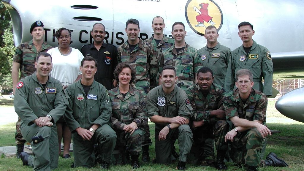 Portrait of a group of 14 servicepeople posing in front of a fighter jet.