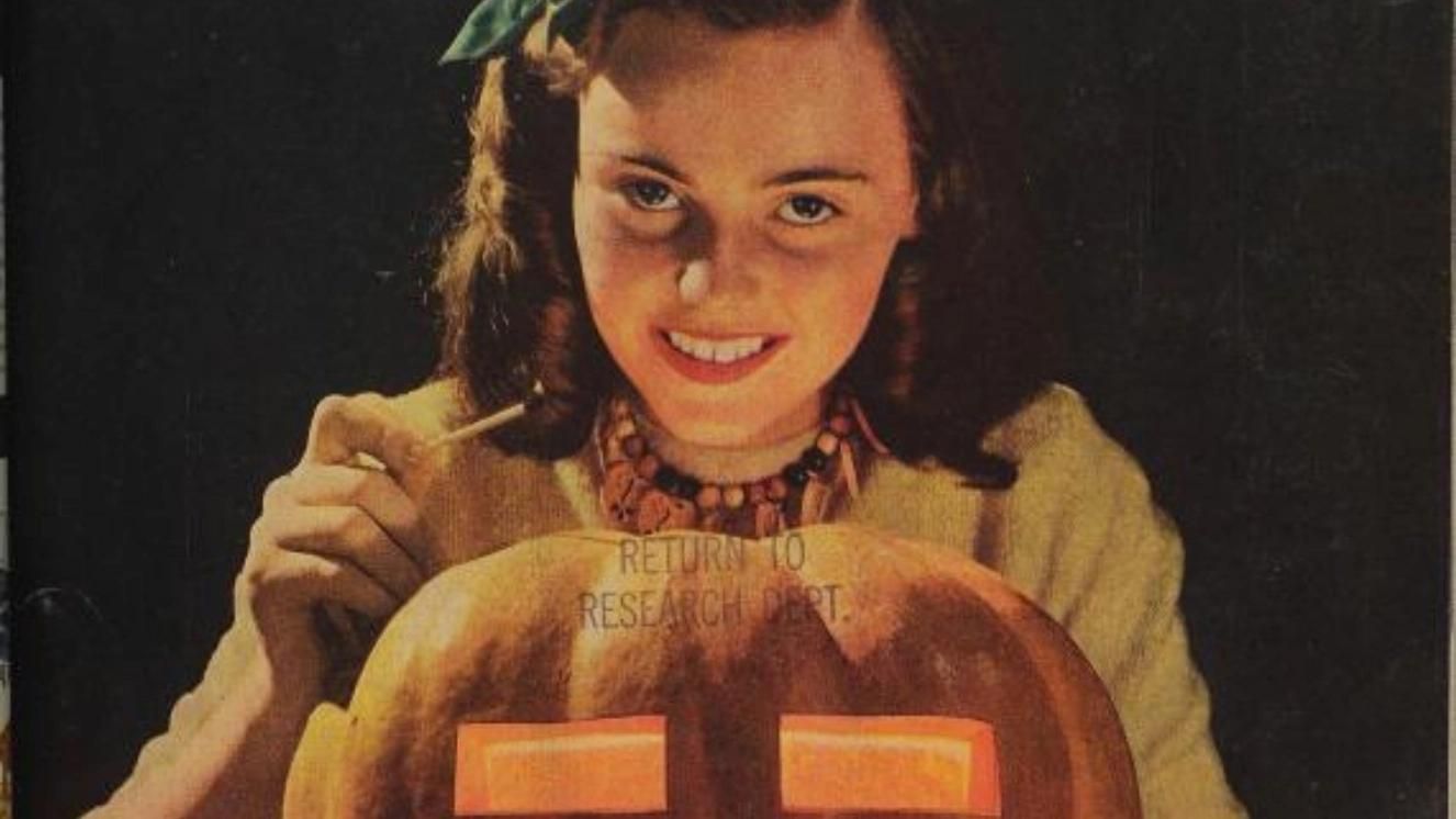 Smiling woman carving a jack-o'-lantern during World War 2 rationing.