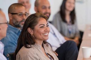 A young woman smiles, surrounded by adult students.