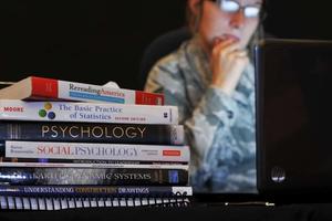 A woman looks at her computer next to books.