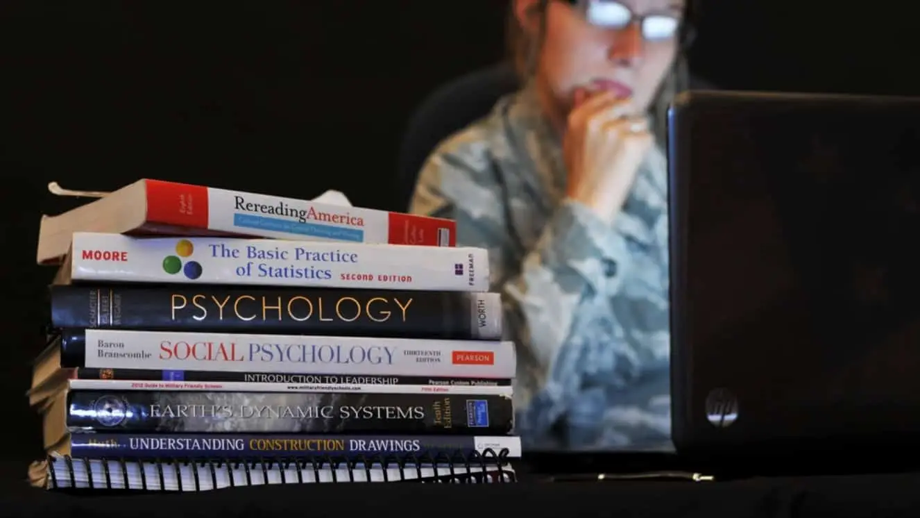 A woman looks at her computer next to books.