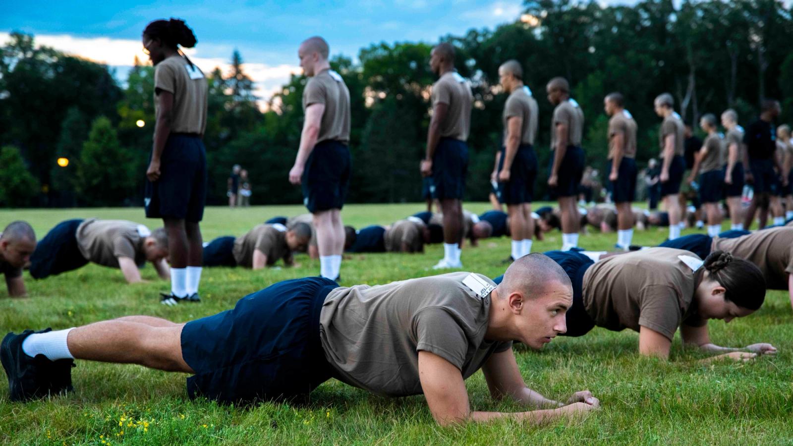 Two rows of naval recruits plank as part of basic training.