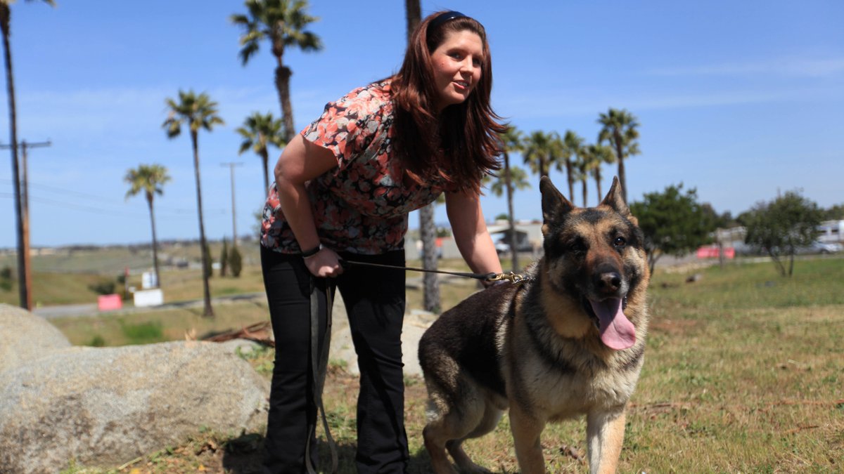 A woman stands with a dog at an adoption ceremony.