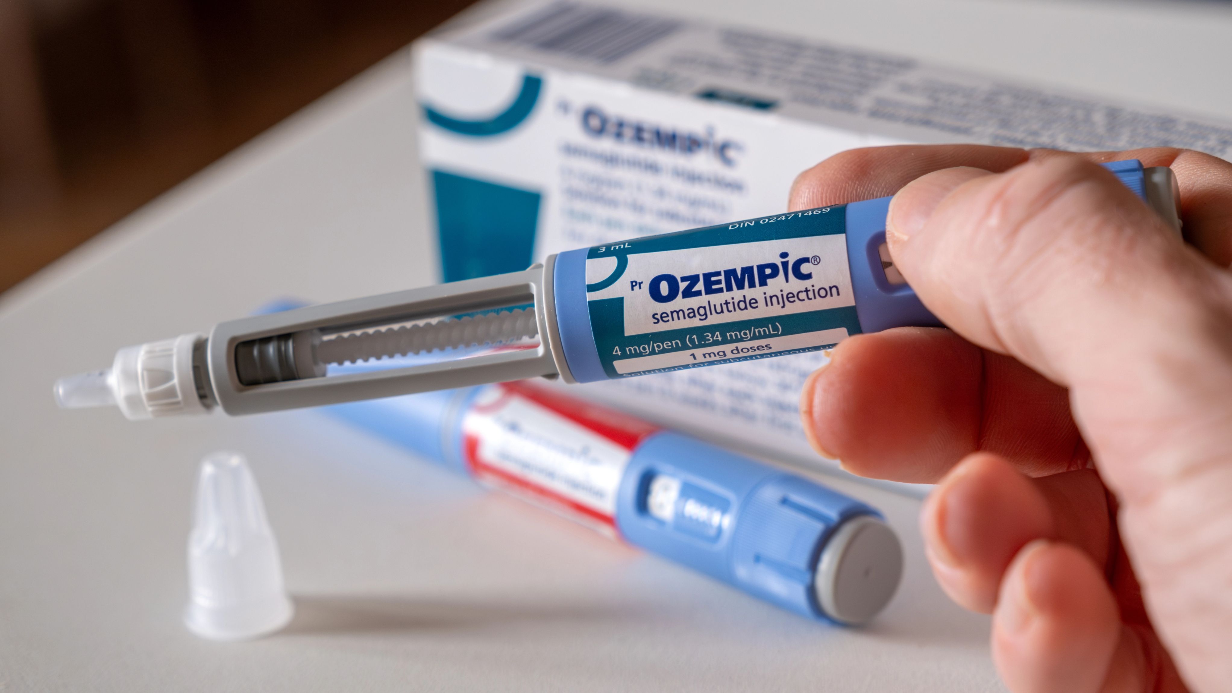A close-up of a hand holding an Ozempic pen.