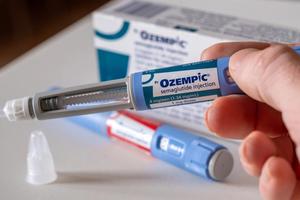 A close-up of a hand holding an Ozempic pen.