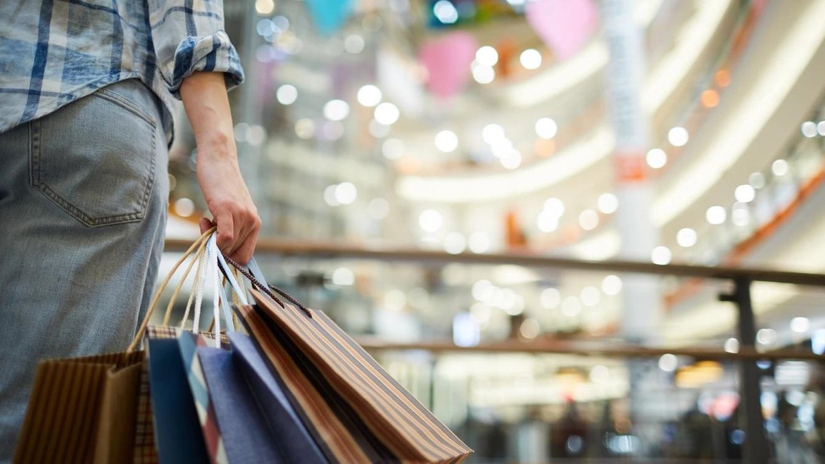 Person holding shopping bags in brightly lit mall, suggesting Black Friday deals for U.S. veterans.