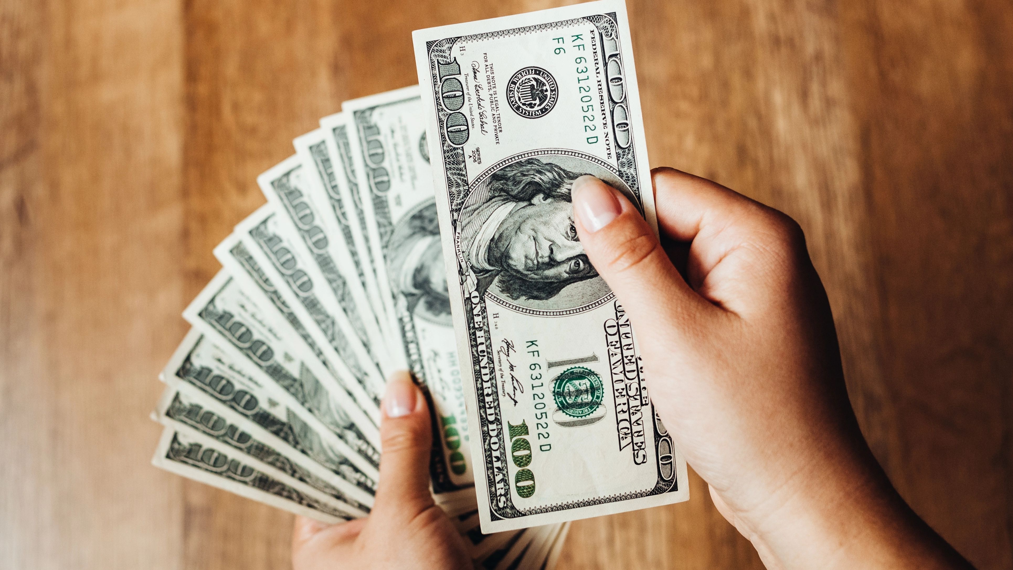 Closeup of hands counting 100-dollar bills.