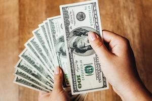 Closeup of hands counting 100-dollar bills.