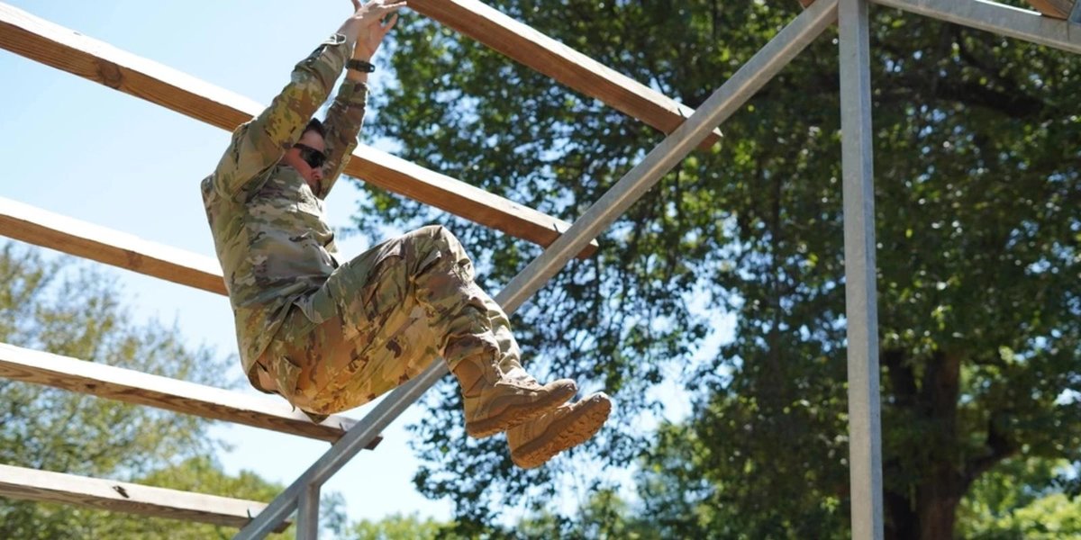 Air Force member in uniform navigating an outdoor obstacle course.