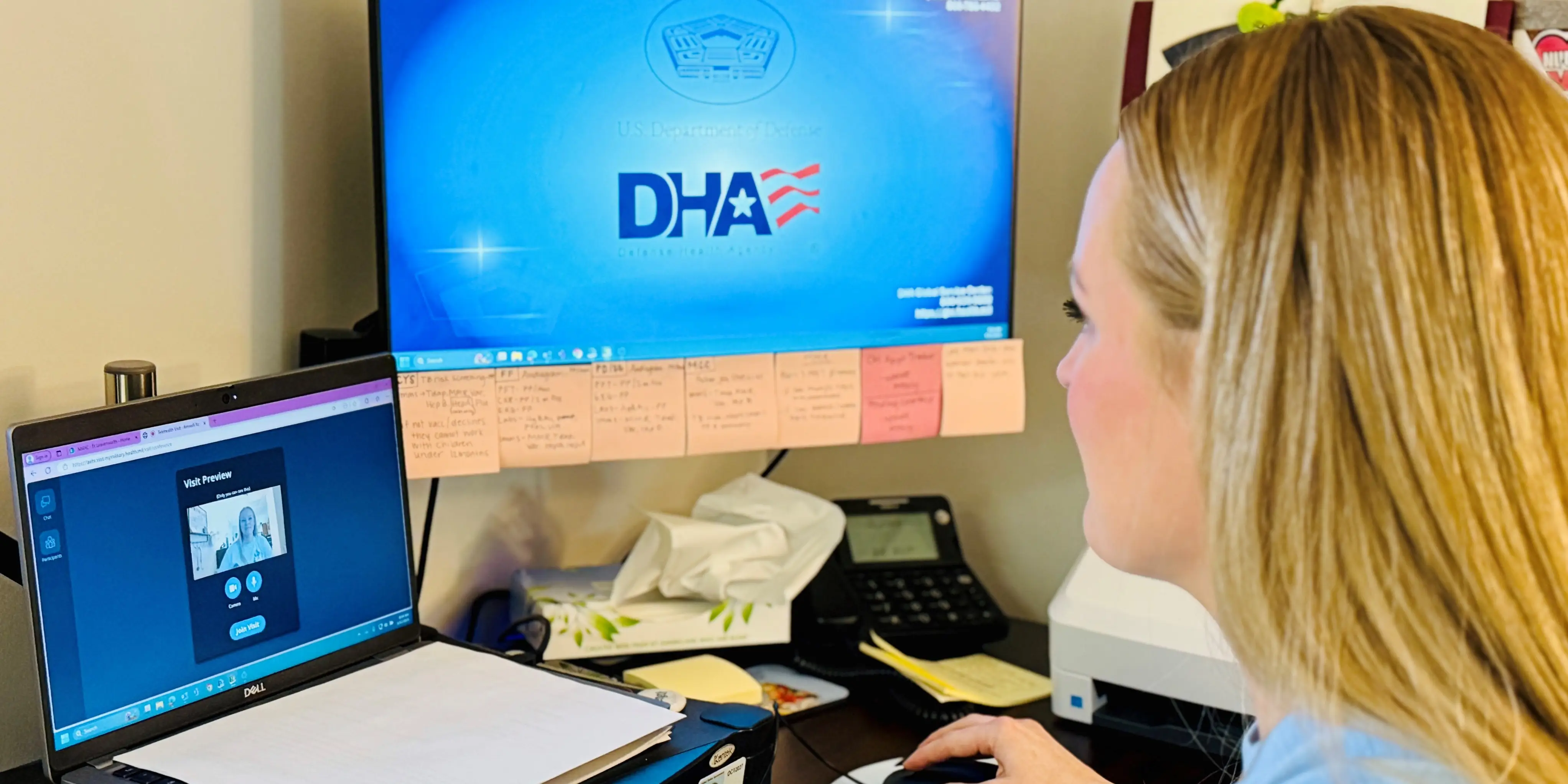 Seen from behind, A female doctor conducts a telemedicine session in front of a laptop.