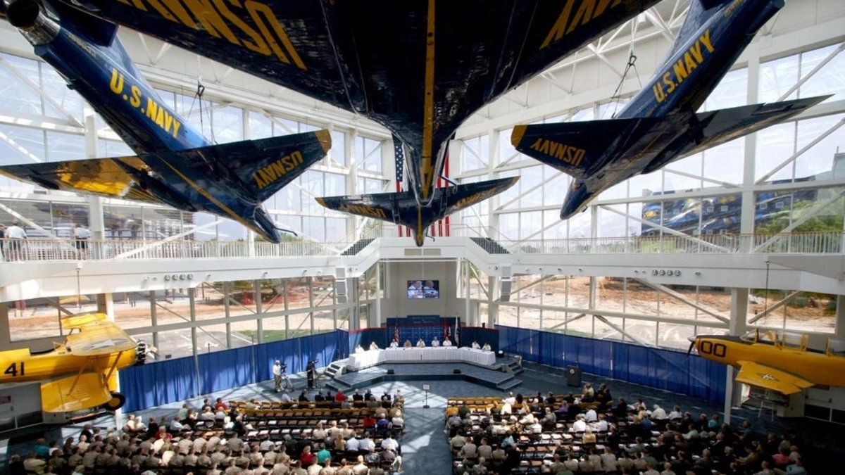 U.S. Navy Blue Angels jets displayed in a museum atrium with audience below