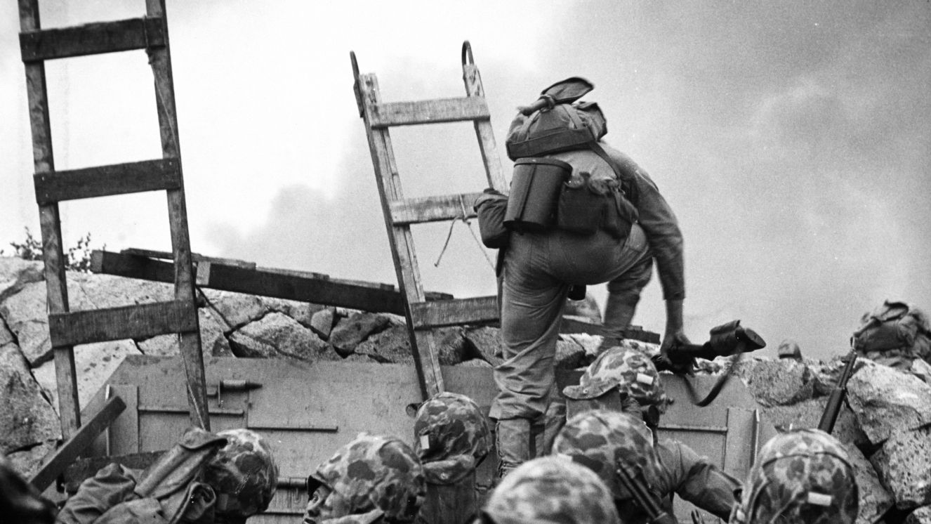 First Lieutenant Baldomero Lopez, USMC, leads the 3rd Platoon, Company A, 1st Battalion, 5th Marines over the seawall on the northern side of Red Beach, as the second assault wave lands, 15 September 1950, during the Inchon invasion.