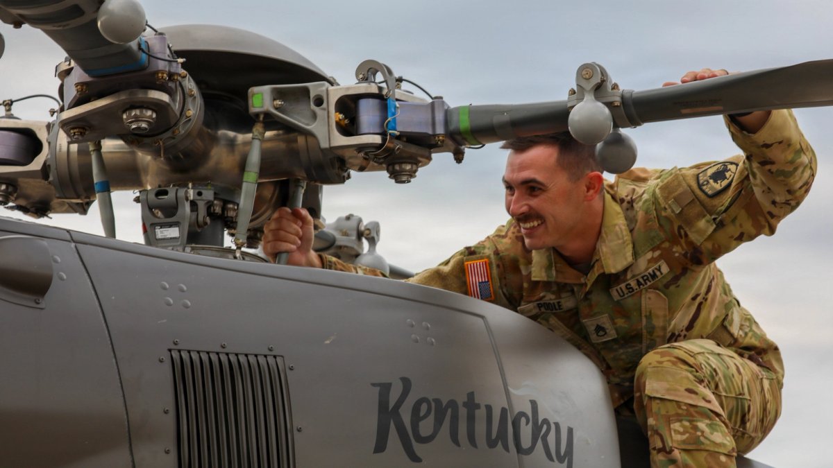 A serviceman checks a propeller on a helicopter.