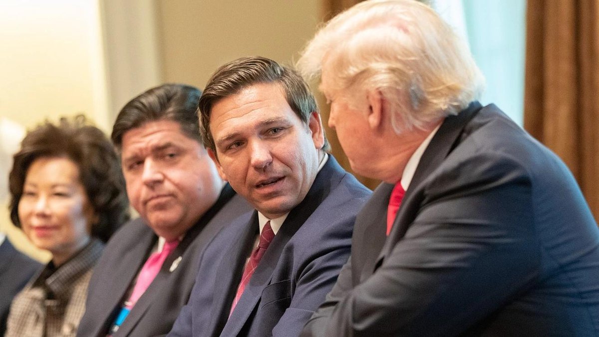Ron DeSantis in discussion with officials at a meeting table