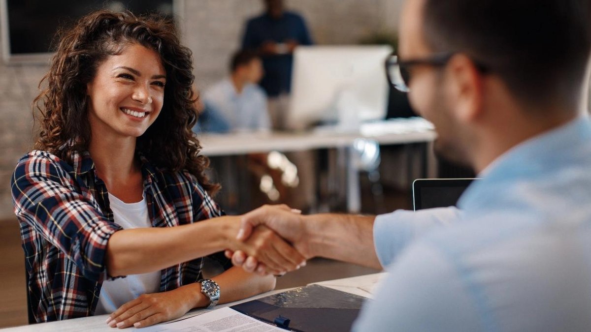 Veteran shaking hands with a woman in an office setting, discussing job opportunities.