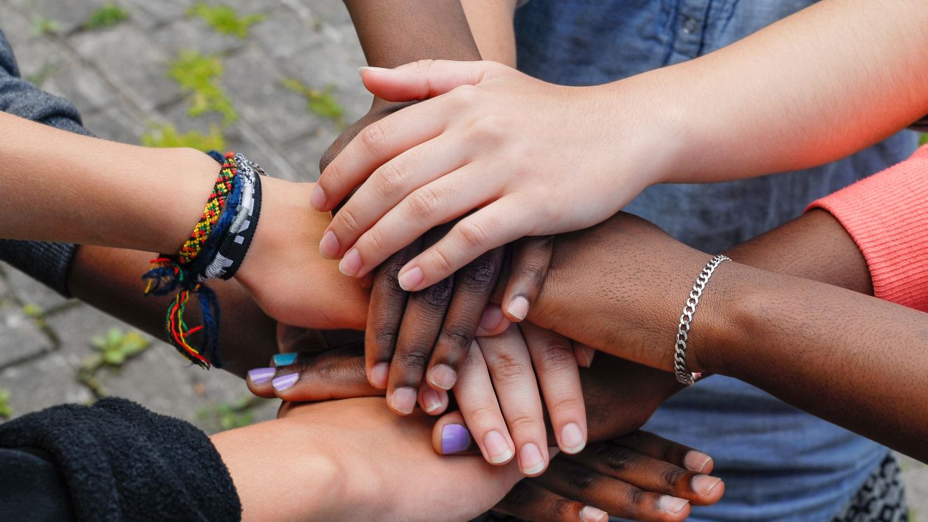 Teenagers joining hands together.