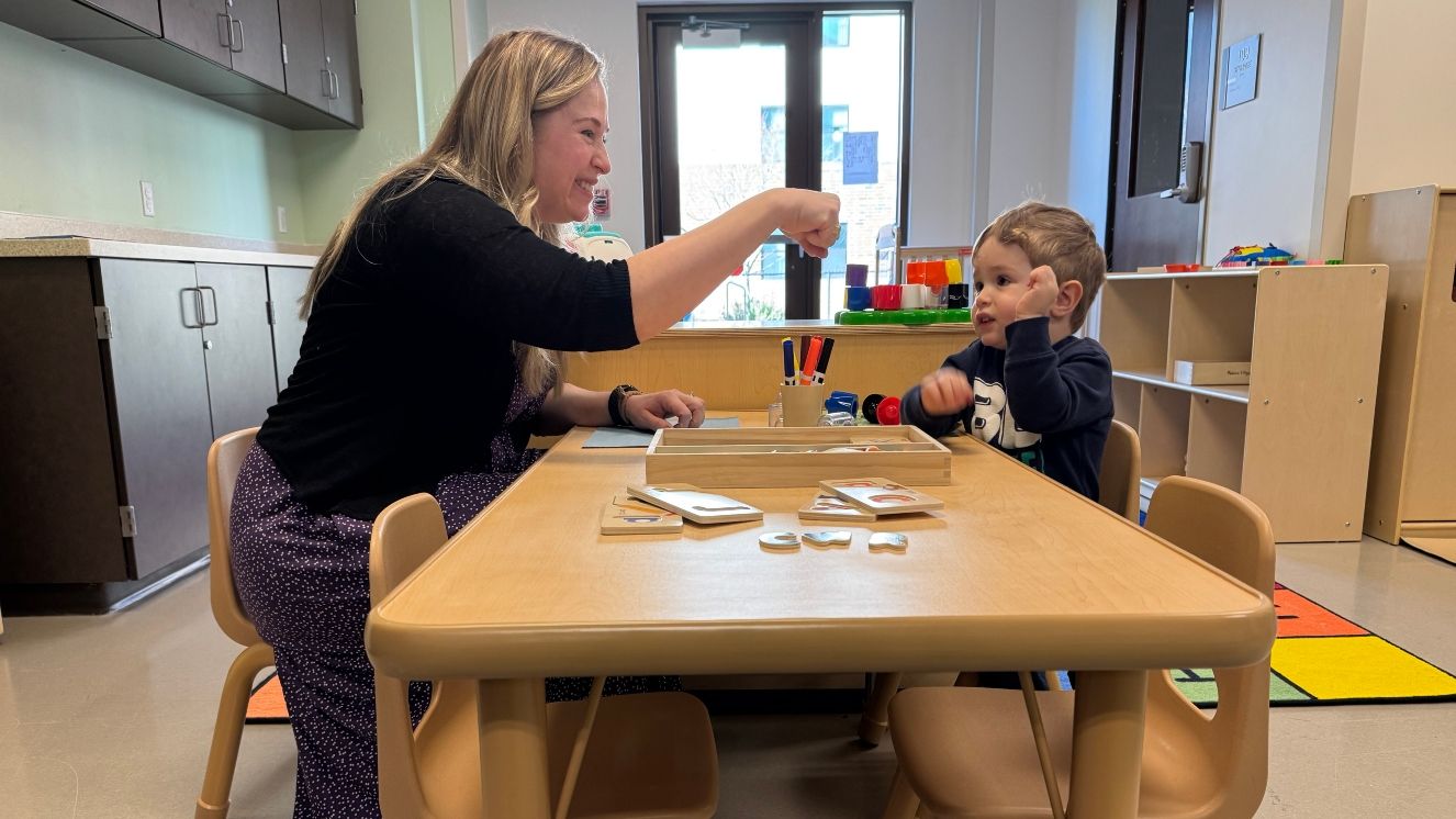 A mom fist bumps with her toddler son in a YMCA child care center.