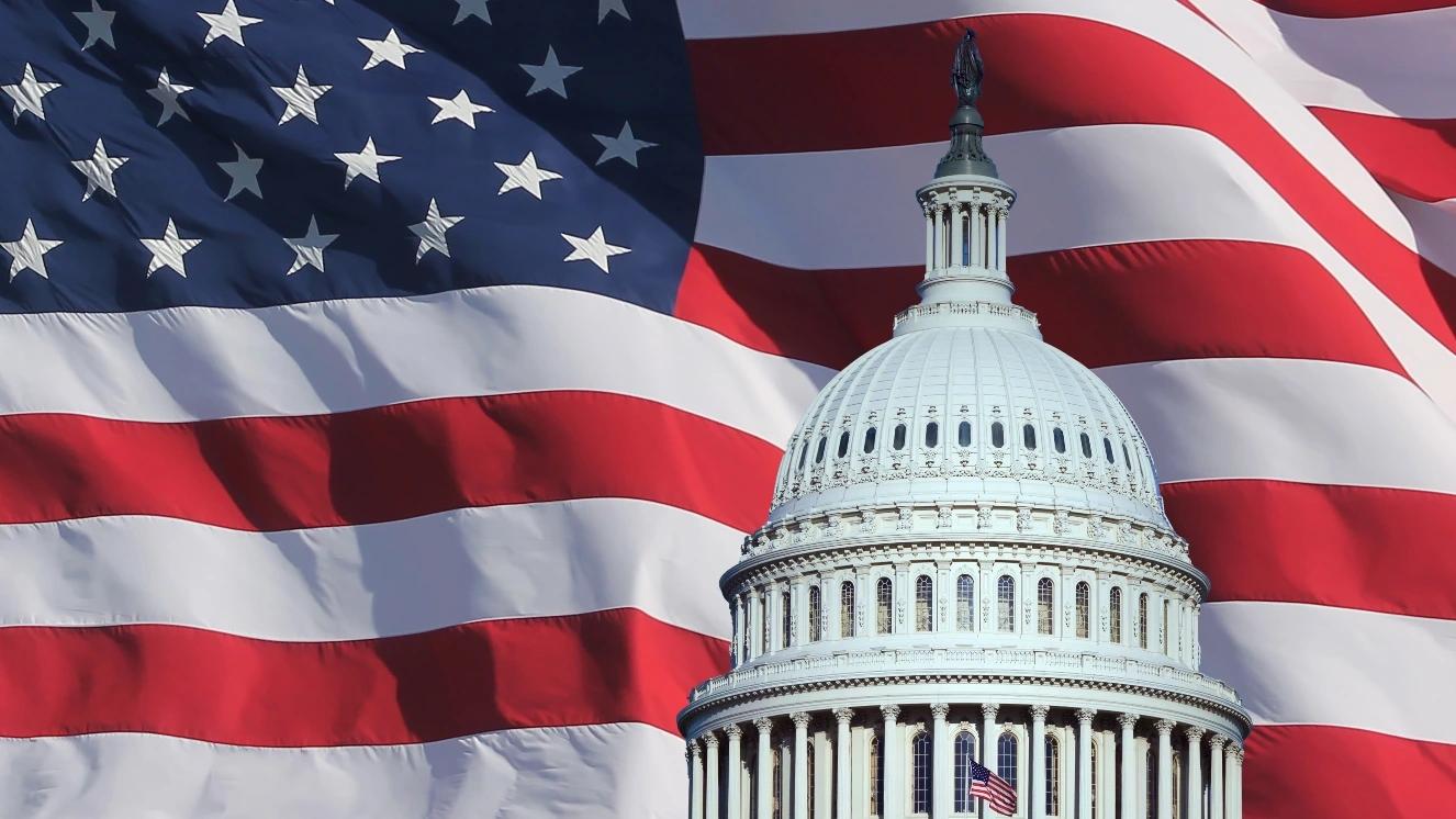 Close up of the US capitol building dome with US flag backdrop.