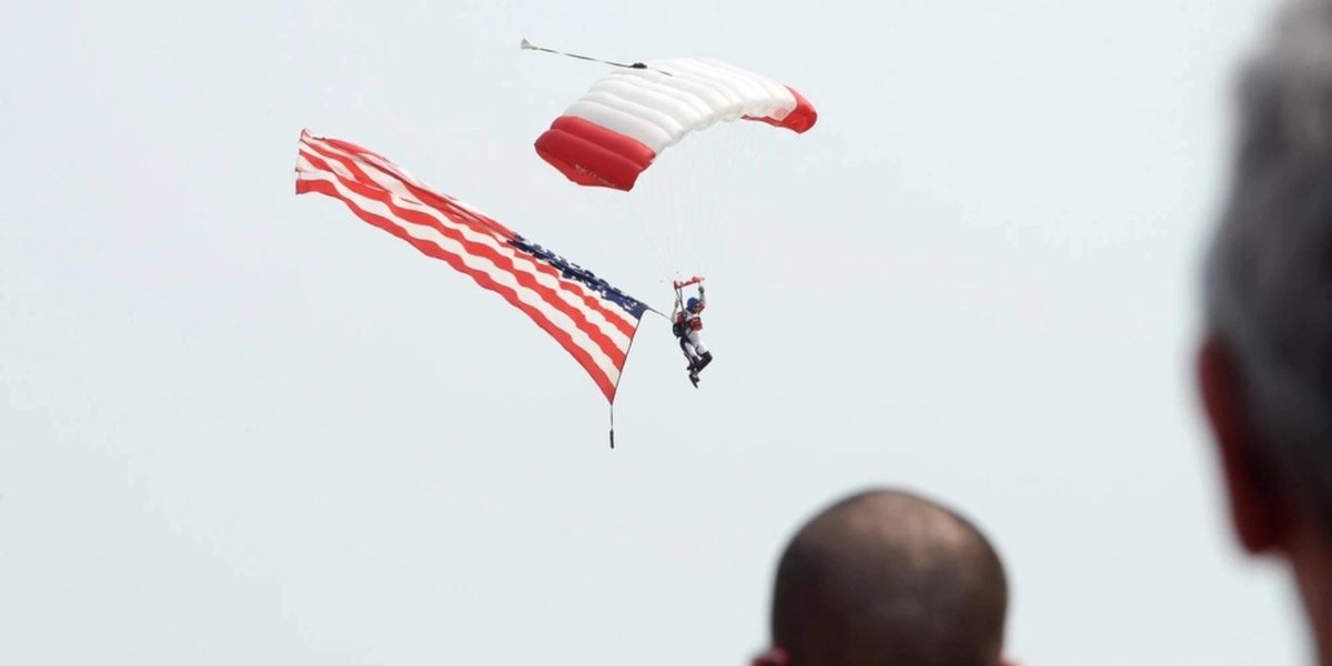 Parachutist with American flag canopy descending at air show event