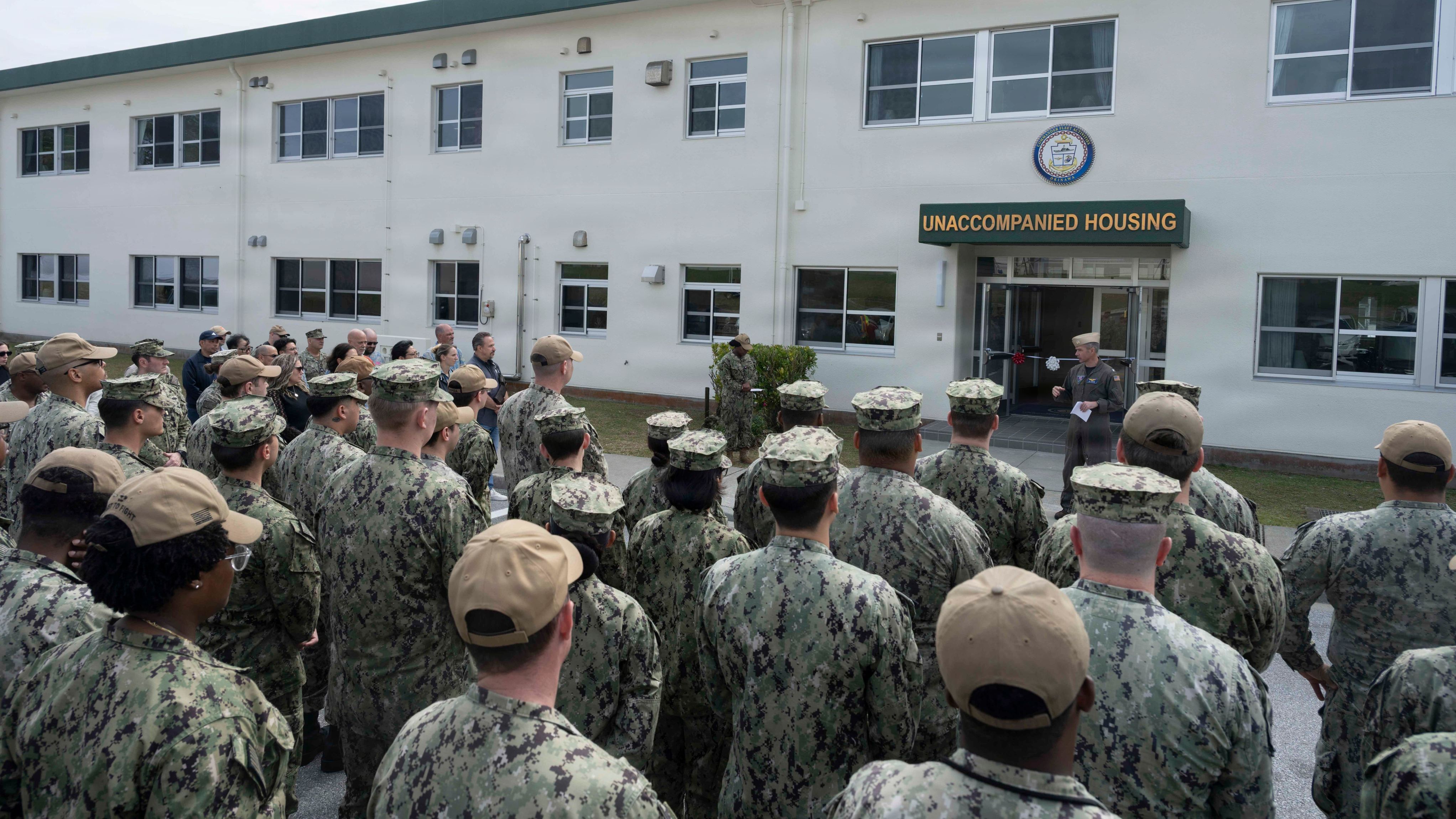 Large group of soldiers being addressed in front of new military housing.