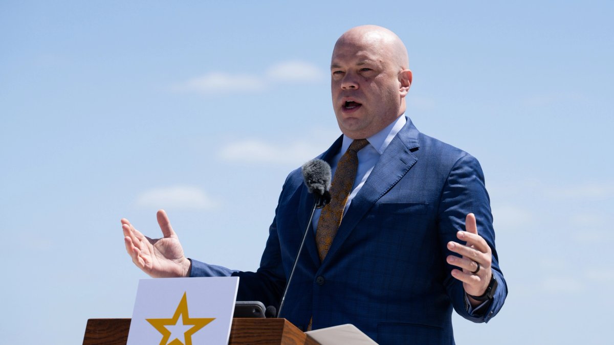 Adam Telle gestures as he speaks at a podium outdoors.