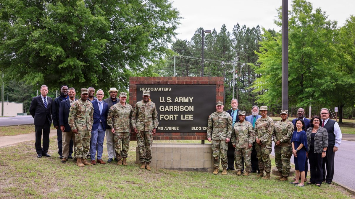 Groups of soldiers stand on either side of a Fort Lee gate sign.